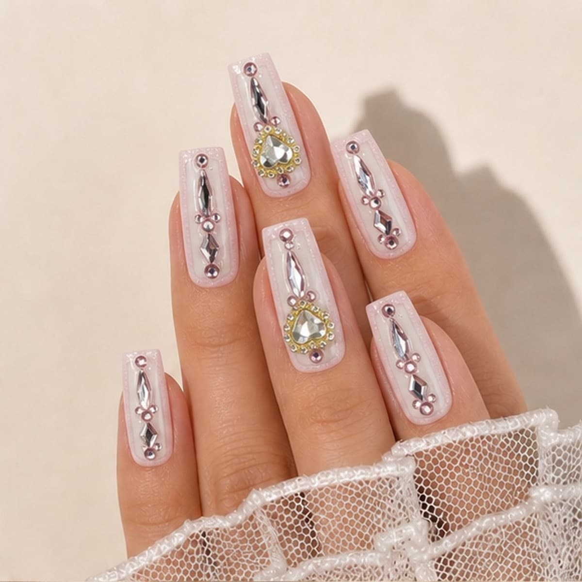 Amour crystal heart sculpture press-on nails worn on a relaxed hand against a cream background