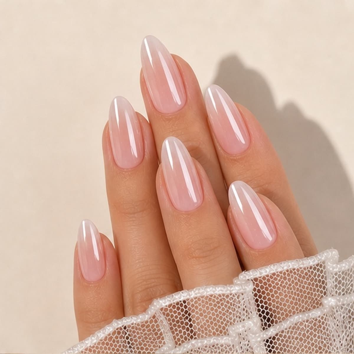 Aurore blush ribbon French press-on nails worn on a relaxed hand against a cream background