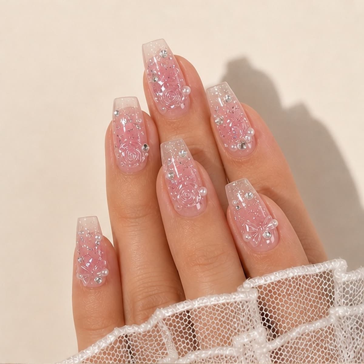 Camélia rose crystal ballet press-on nails worn on a relaxed hand against a cream background