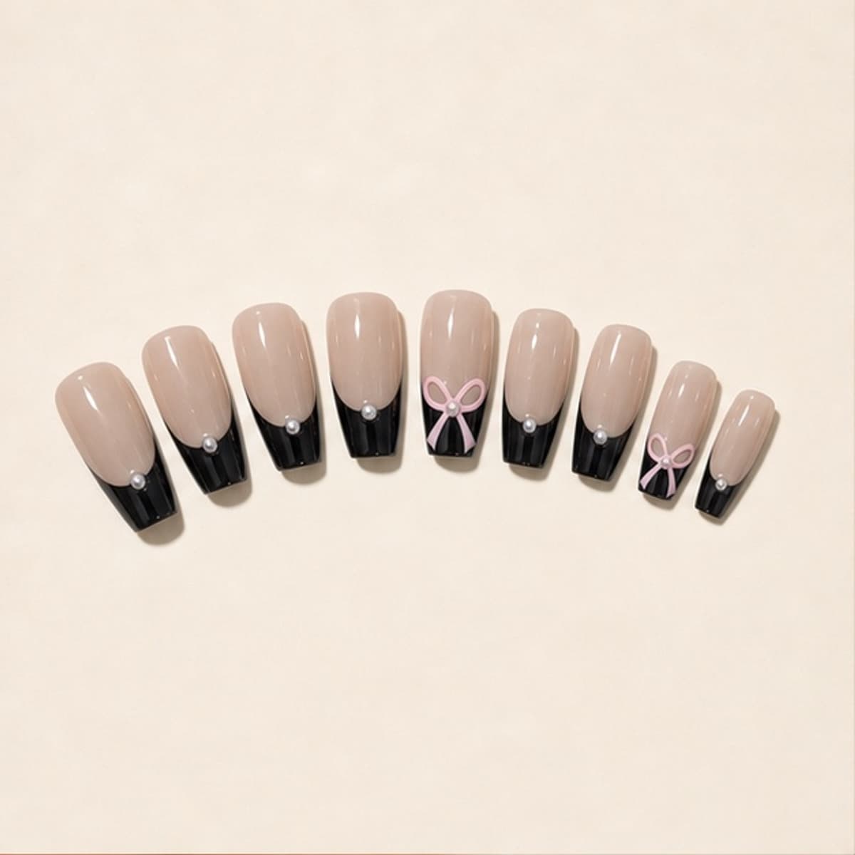 Coquette black French and pink bow press-on nail set arranged in a fan on an ivory background