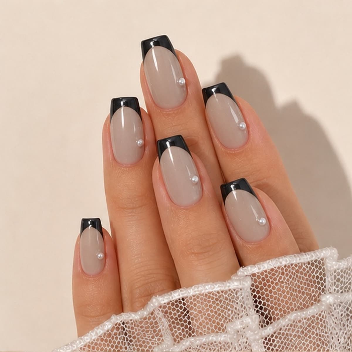 Coquette black French and pink bow press-on nails worn on a relaxed hand against a cream background
