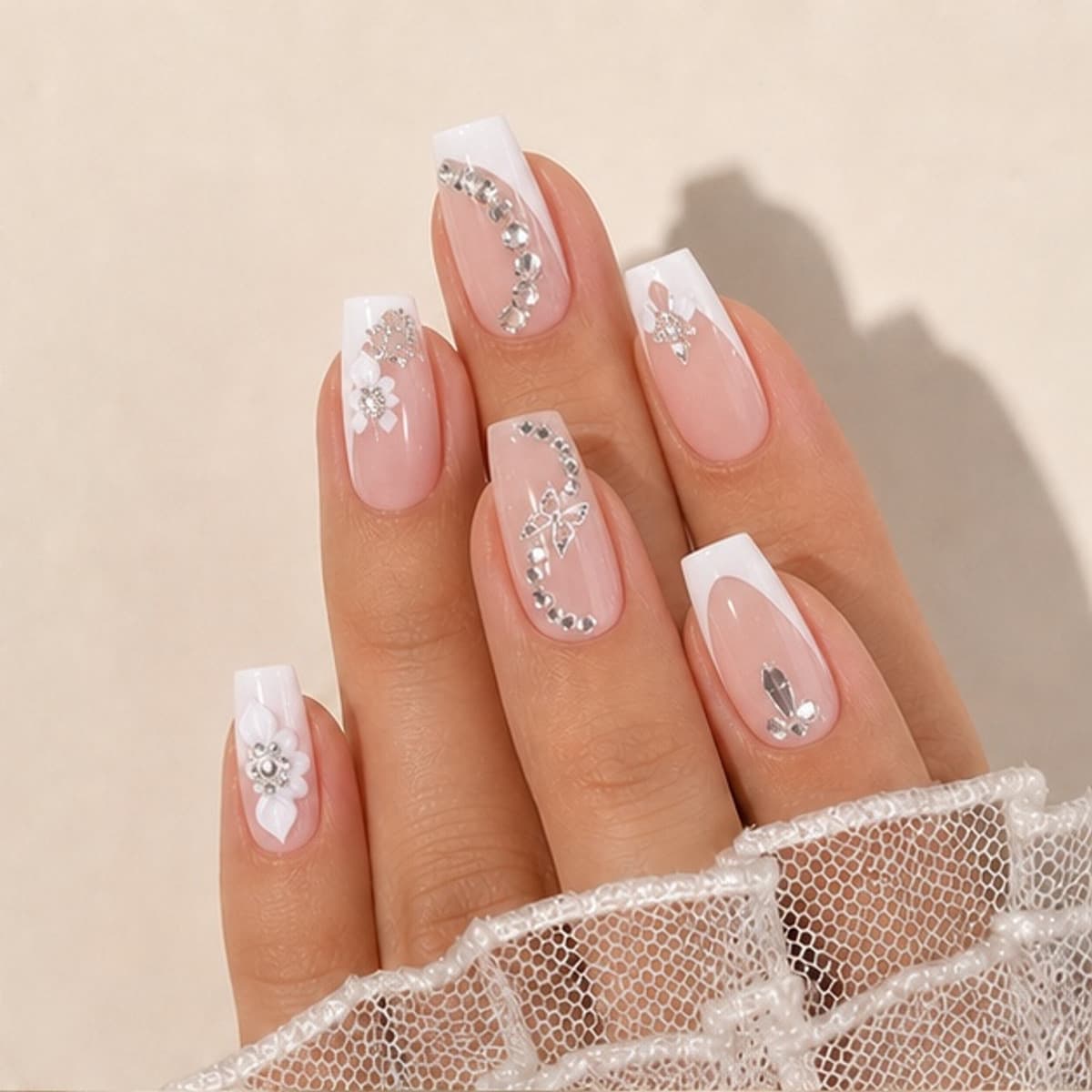 Étoile crystal flower chain French press-on nails worn on a relaxed hand against a cream background
