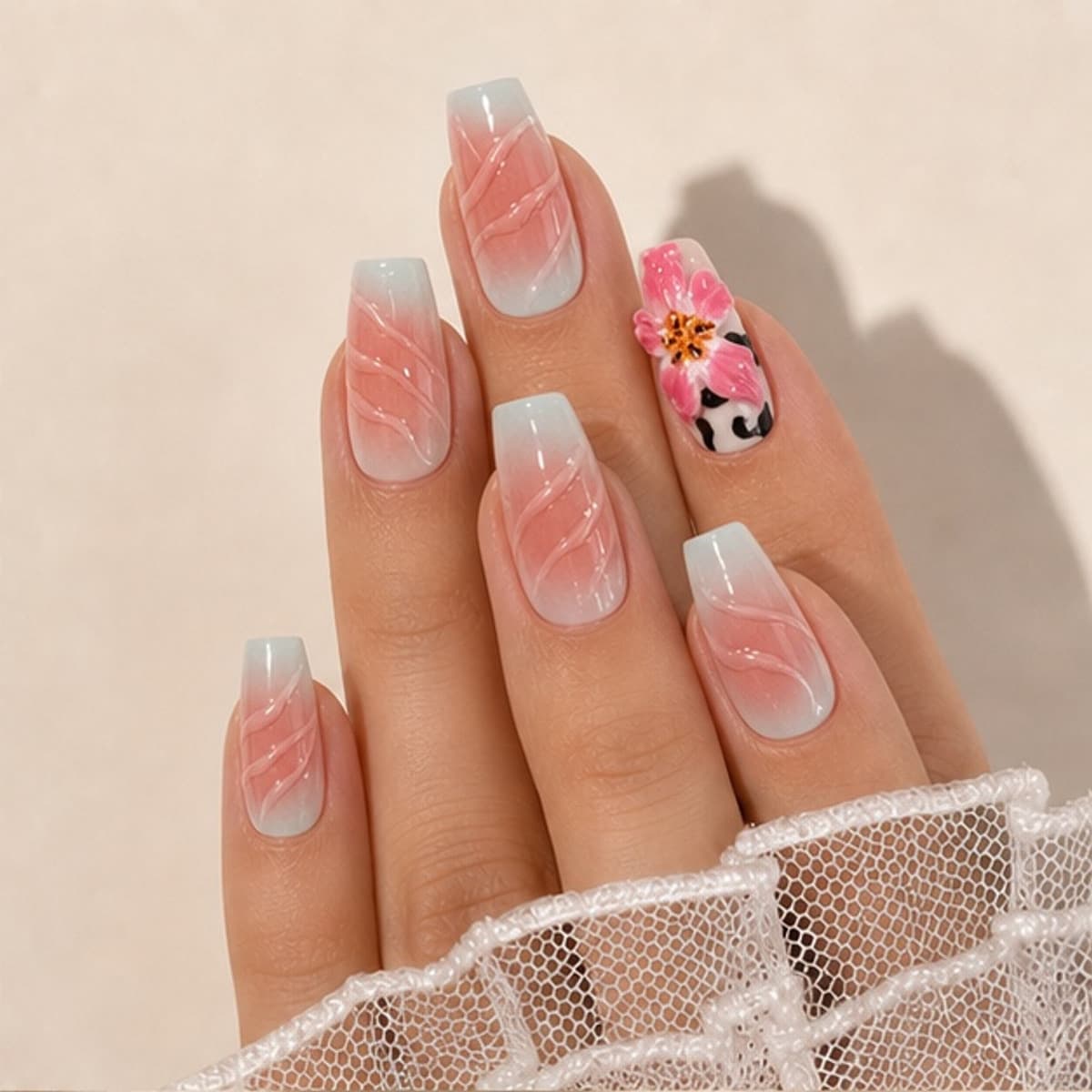 Héritage sculpted lily and zebra press-on nails worn on a relaxed hand against a cream background