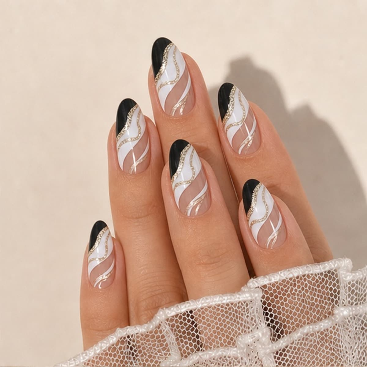 Minuit black-and-white ripple press-on nails worn on a relaxed hand against a cream background